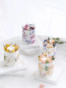 Detailed view of handmade scented candles decorated with colorful dried flowers and wicks