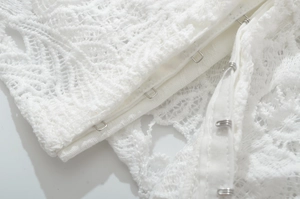 Detail shot of the delicate white lace fabric and secure metal hook-and-eye closure