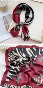 Détail d'un foulard en soie bordeaux et crème avec imprimé zèbre noué en nœud