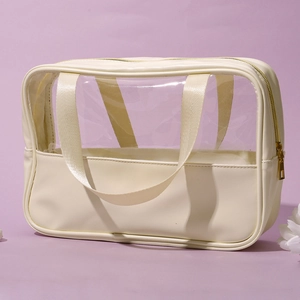 Detail of cream PU leather and clear PVC makeup bag with dual handles and gold zipper