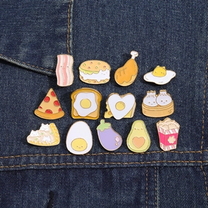 Collection de 12 pin's émaillés colorés présentés sur un tissu en denim bleu foncé
