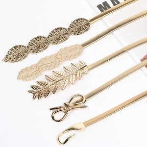 Detail of various gold spring waist belts featuring leaf, feather, and bow metal buckles