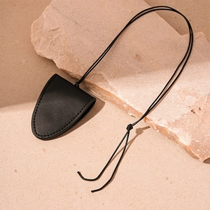 Detail of black faux leather magnetic triangle pouch with stitching on stone background