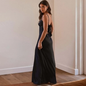 Détail d'une robe longue en satin noir élégante avec dos nu et un nœud papillon délicat