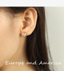 Detailed close-up of heart-shaped zircon earrings with gold setting worn by model