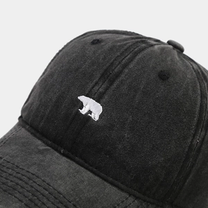 Close-up of vintage washed black baseball cap featuring detailed white bear embroidery