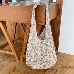 Detailed shot of a floral print cotton tote bag hanging on a rustic wooden cabinet side