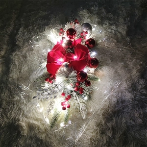Close-up of lighted Christmas teardrop wreath with red berries and velvet ribbon bow