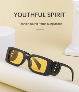 Detail of square sunglasses with black frame, yellow lenses and interlocking metal hinge