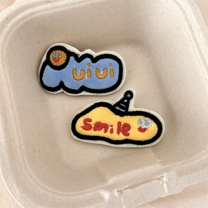 Detailed close-up of cute cartoon embroidered patches with vivi and smile text patterns