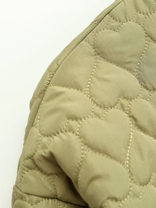 Macro detail of heart-shaped quilted stitching on olive green jacket fabric