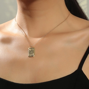 Detail of a vintage gold tarot necklace featuring The Sun engraving worn by a model