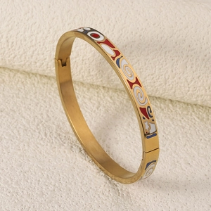 Detailed close-up showing vibrant red, blue, and white enamel patterns on a gold steel bangle