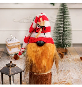 Christmas gnome ornament with red striped hat and orange beard on a festive wooden base