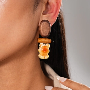Detail of wooden geometric earring with amber resin bear pendant worn by model
