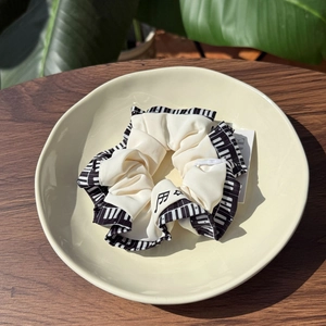 Close-up of cream hair scrunchie with black piano key print and music note embroidery