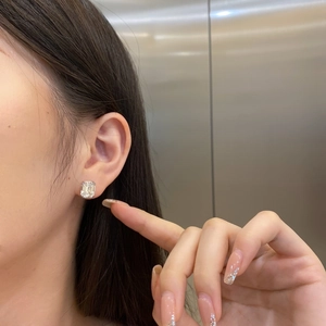 Macro side view of S925 sterling silver emerald cut zircon stud earring worn on ear