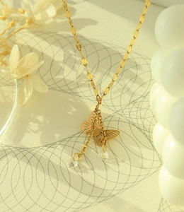 Detail of gold butterfly pendant with sparkling zircon tassels and sequin chain