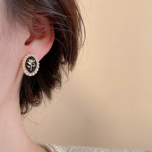 Gros plan sur des boucles d'oreilles ovales noires vintage avec rose dorée et perles