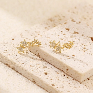 Detailed view of gold S925 silver star earrings with sparkling diamonds on stone