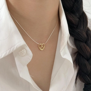 Minimalist 925 sterling silver heart necklace with golden bow pendant worn on neck