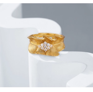 Detail of gold ruffled texture ring with sparkling white diamonds on geometric stand