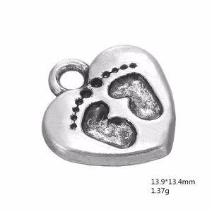 Detailed view of heart-shaped alloy pendant with baby footprint relief in antique silver