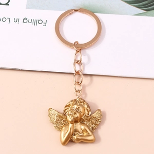 Polished golden angel keychain with detailed wings and thinker pose on gift card