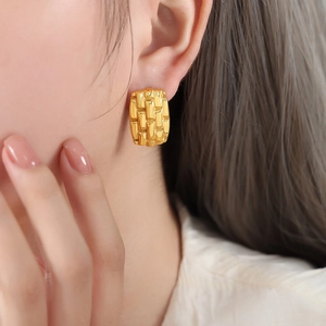 Golden square earrings with woven texture on female model, elegant geometric jewelry
