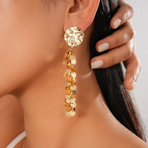Macro side view of long gold layered tassel earrings with hammered texture on model