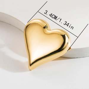 Detail showing the 3.4cm polished golden heart brooch with a high-gloss metallic finish