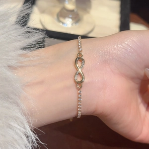 Close-up of gold infinity charm bracelet with sparkling zircons on a model wrist