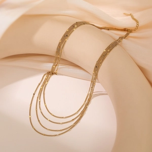 Layered 18K gold plated stainless steel necklace on beige silk background