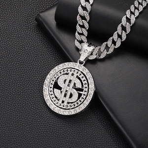 Macro detail of iced out spinning dollar pendant with white rhinestones on Cuban link chain