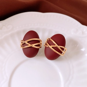 Vue détaillée de boucles d'oreilles bordeaux vintage avec détails de fil doré tressé