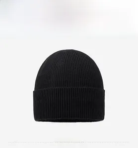 Close-up of black ribbed knit beanie featuring a metallic circular logo on the folded cuff