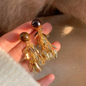 Close-up of elegant gold leaf tassel earrings featuring vintage resin beads decoration