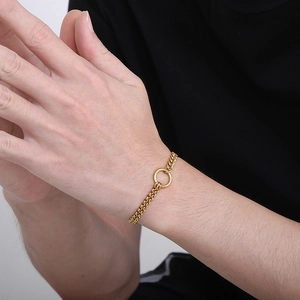 Gold double chain stainless steel bracelet with a central ring charm on a male wrist