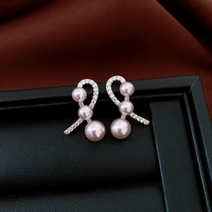Detailed macro view of silver bow earrings with sparkling zircons and three purple pearls