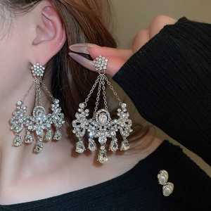 Détail de boucles d'oreilles argentées avec cristaux brillants et longues pampilles
