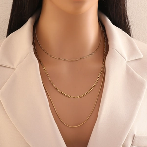 Detail of a gold-toned triple-layered necklace with Cuban, Figaro, and snake chains