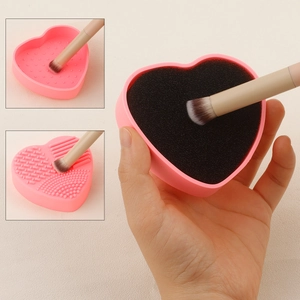 Detailed view of pink heart-shaped silicone makeup brush cleaner with dry sponge pad