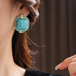 Macro shot of vintage style silver needle earrings with blue turquoise and small diamonds