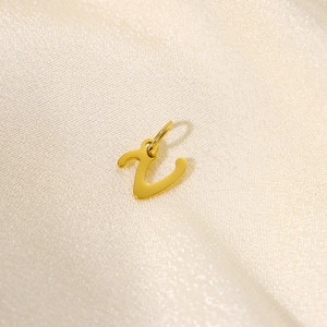 Macro shot of a cursive letter Z gold charm on silk fabric for jewelry making