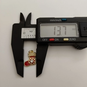 Detail shot showing a red enamel Christmas sock pendant width measured at 13.7mm