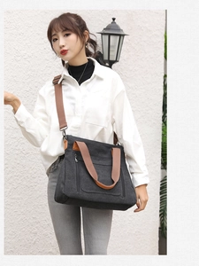 Minimalist black canvas tote bag with brown straps worn as a stylish shoulder bag