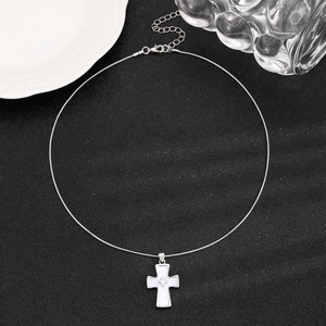Macro detail of silver cross pendant necklace with white inlay on black background