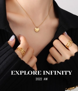 Close-up of gold heart pendant necklace and hollow letter B rings on a model
