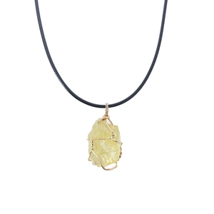 Macro detail of raw yellow citrine stone pendant with handcrafted gold wire wrapping