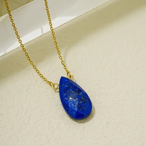 Gros plan du pendentif goutte en lapis-lazuli avec surface facettée et chaîne dorée